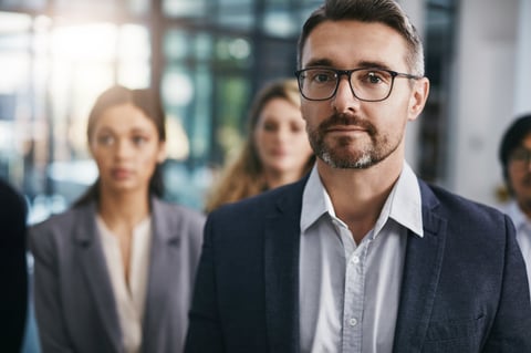 Portrait of a mature businessman standing in an office with his colleagues in the background